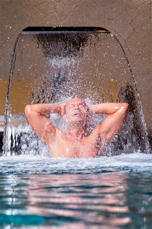Persona bajo cascada de agua en spa de Tenerife.