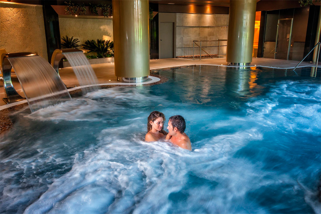 Pareja disfrutando en piscina cubierta de spa en Tenerife.
