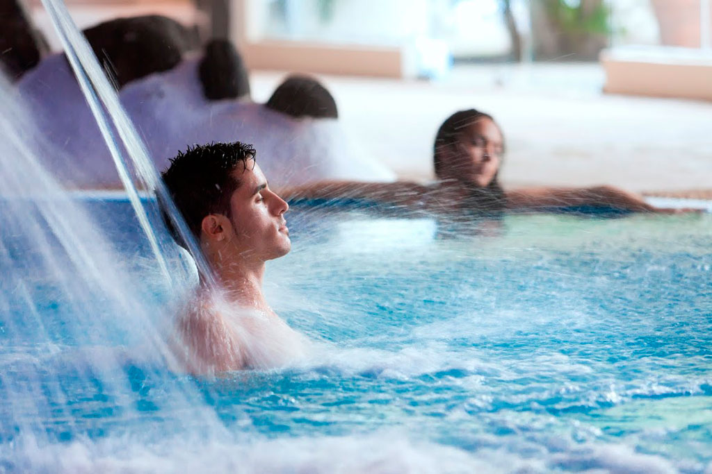 Hombre disfrutando de un chorro de agua en una piscina en Tenerife.
