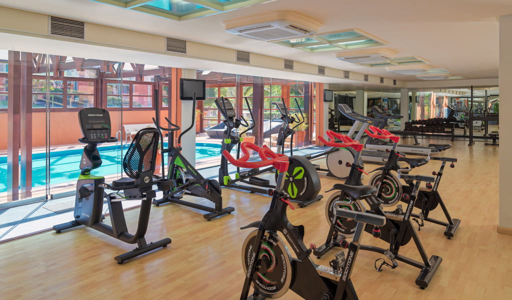 Gimnasio con equipamiento moderno y vista a la piscina en Tenerife.