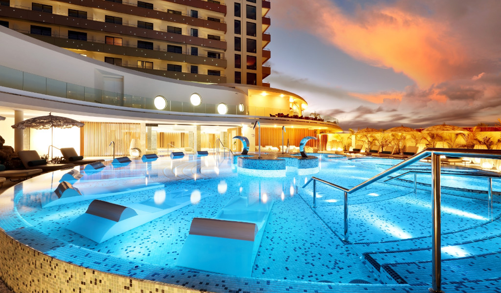 Piscina iluminada al anochecer en hotel de Tenerife.