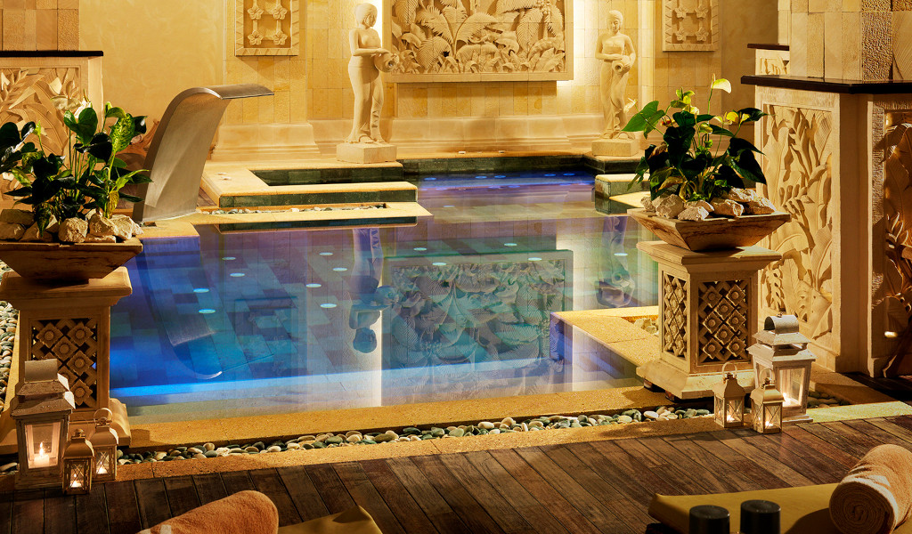 Piscina decorada con esculturas y plantas en un spa de Tenerife.