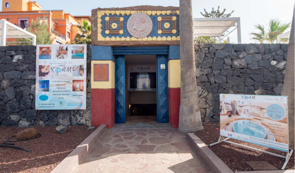 Entrada del spa XQANM con carteles publicitarios en Tenerife.