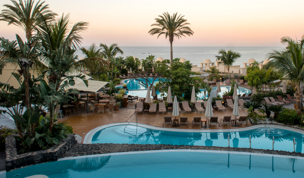 Piscina de hotel en Tenerife con vistas al mar al atardecer.