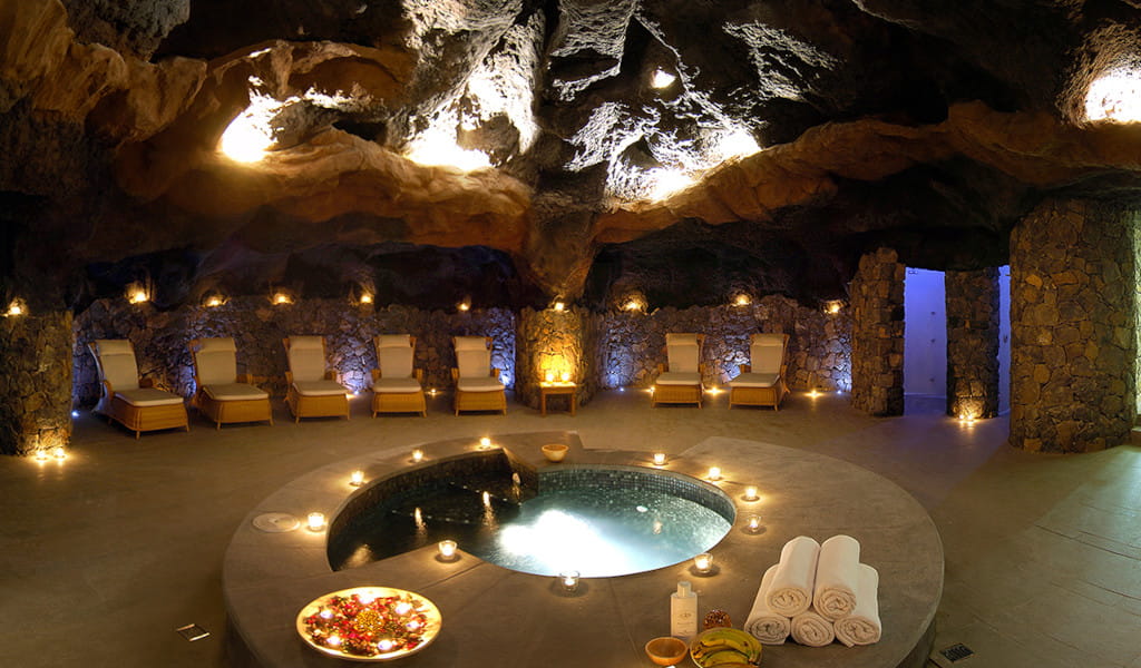 Cueva con jacuzzi rodeado de sillas y velas en un spa en Tenerife.