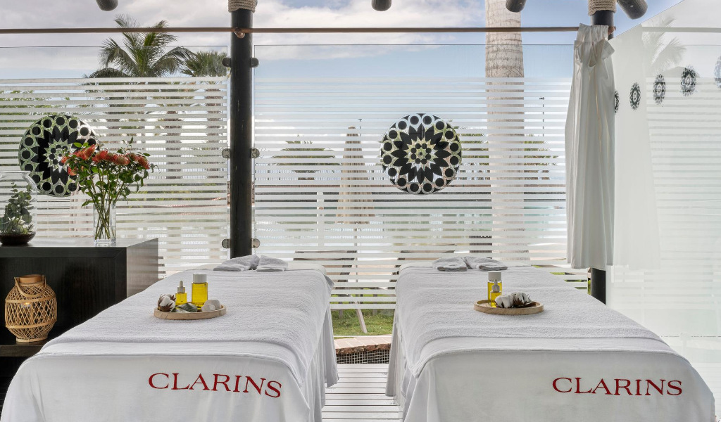 Mesa de masaje con aceites en spa Clarins, Tenerife, junto a ventana decorada.