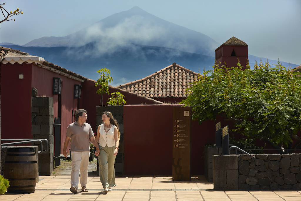 Personas caminando cerca de casas tradicionales con el Teide al fondo en Tenerife.