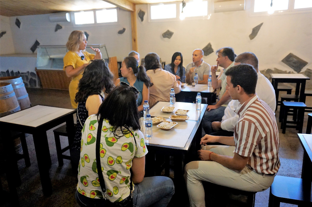 Grupo de personas reunidas en una bodega en Tenerife, compartiendo comida alrededor de mesas.