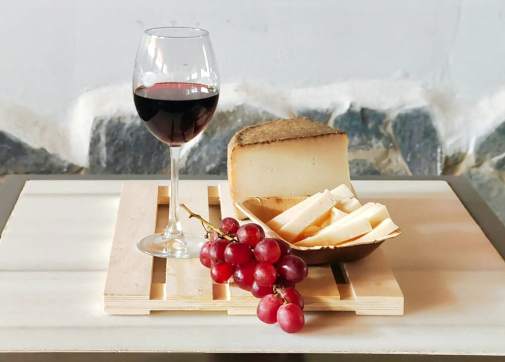 Vaso de vino tinto, queso y uvas rojas sobre tabla en Tenerife.
