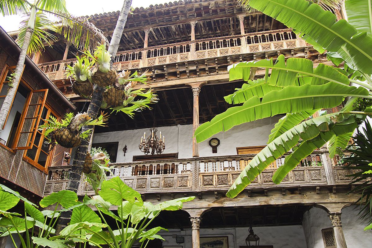 Balcón de madera rodeado de plantas en un edificio tradicional en Tenerife.