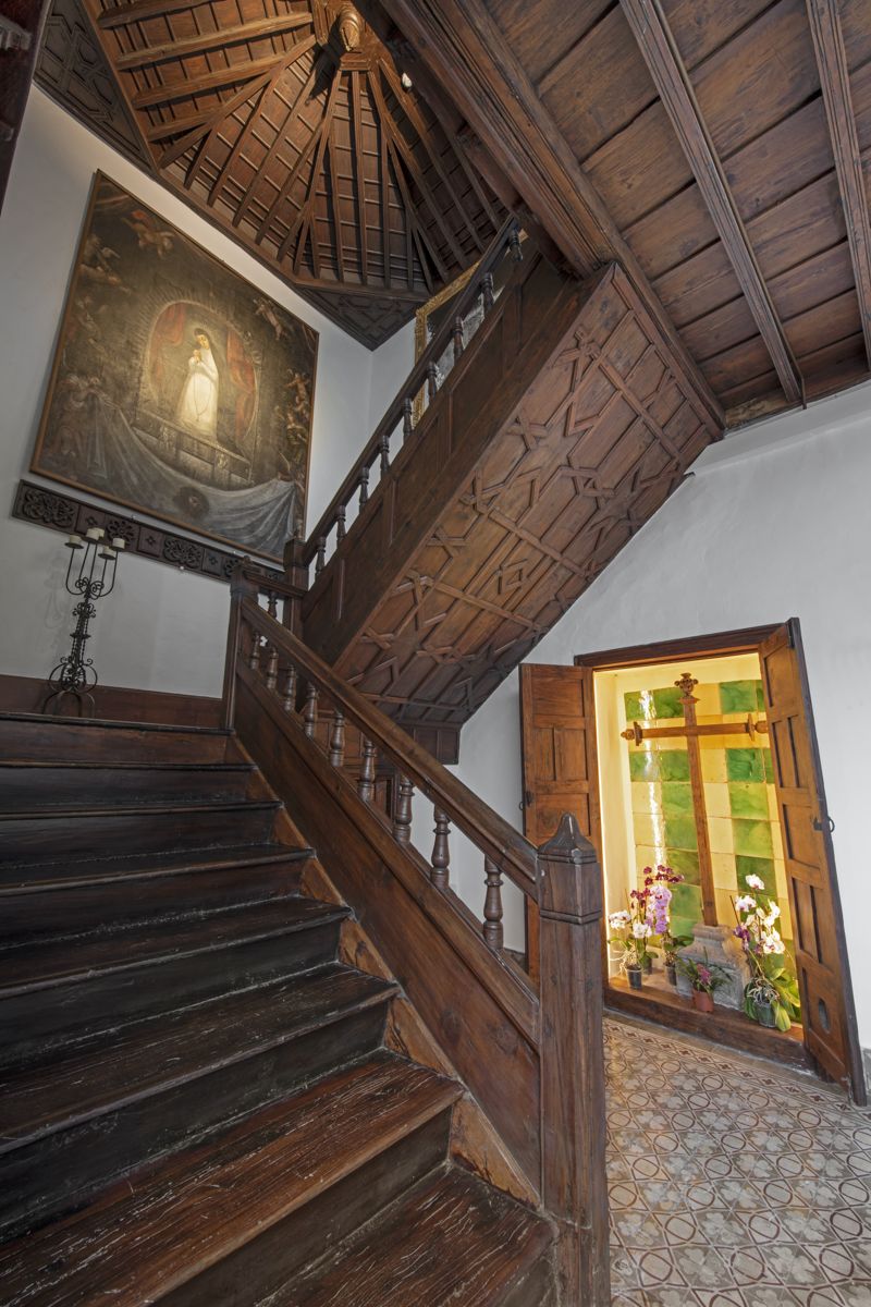 Escalera de madera con cuadro religioso y vitral en una casa de Tenerife.