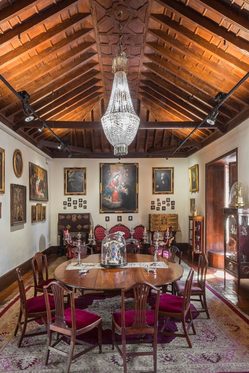 Sala comedor con candelabros, mesa redonda y techo de madera, en Tenerife.