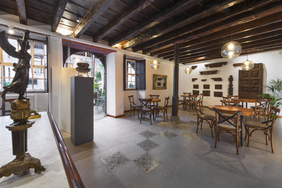 Interior de un café histórico en Tenerife con mesas de madera y decoración clásica.