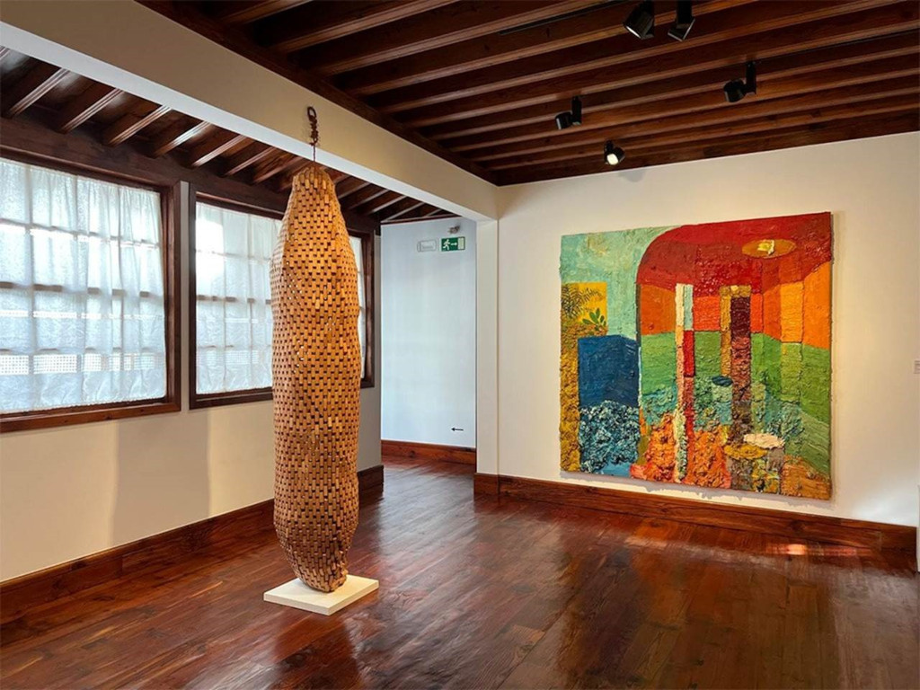 Escultura de madera y cuadro abstracto en sala de arte en Tenerife.
