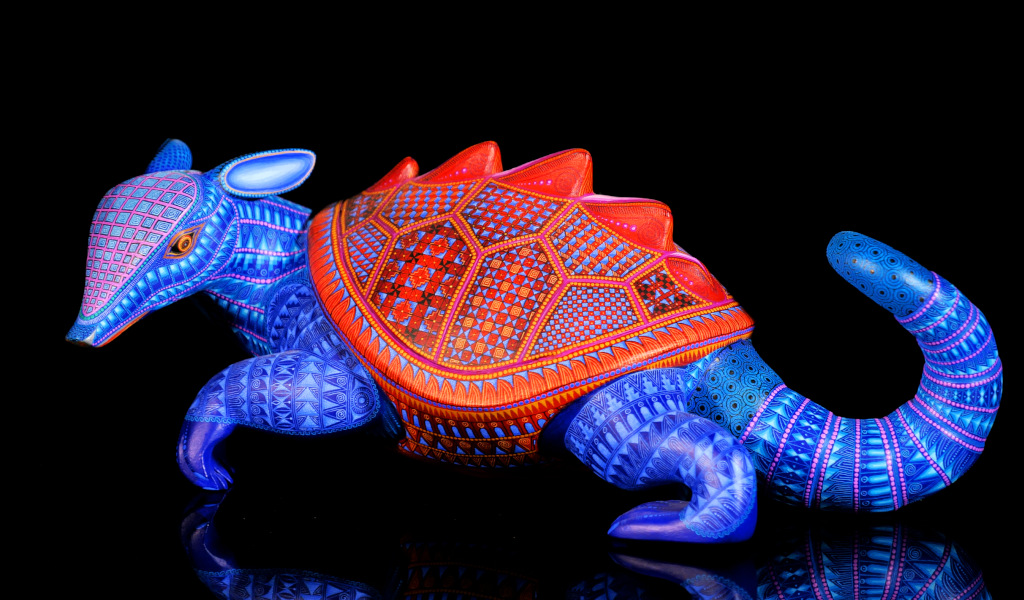 Armadillo de madera tallada con colores vibrantes y diseños geométricos.