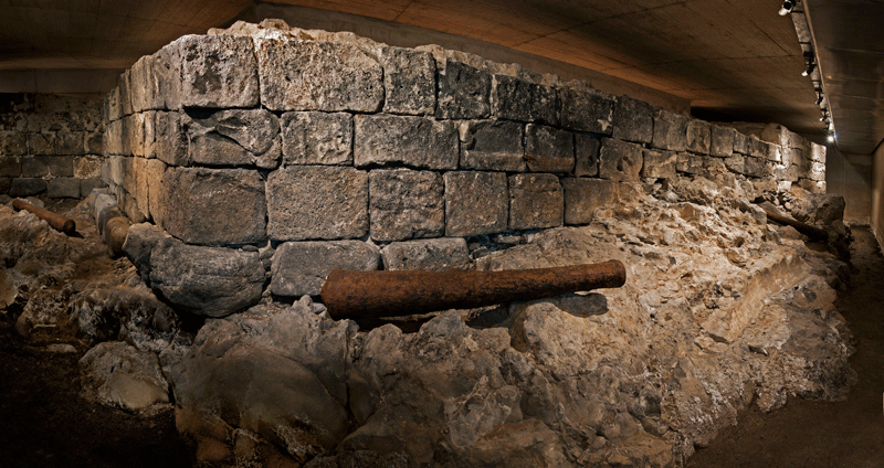 Ruinas de un muro histórico en Tenerife iluminadas bajo un techo de concreto.