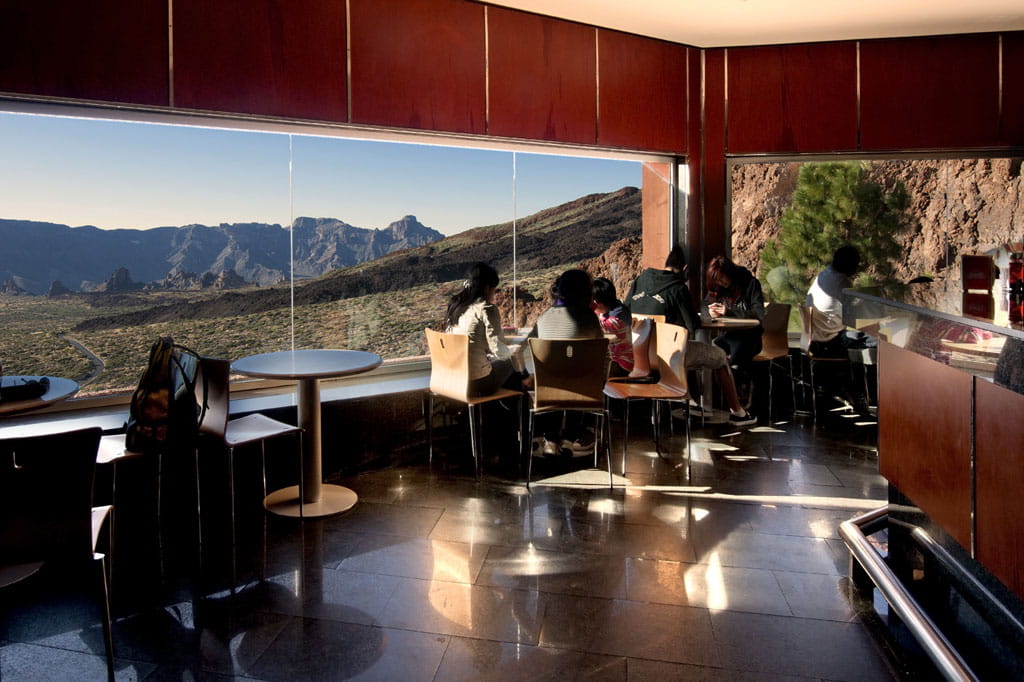 Vista del Teide desde un café en Tenerife con personas sentadas cerca del ventanal.