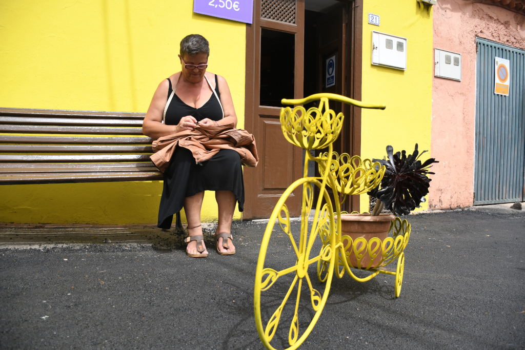 Mujer sentada en banco junto a bicicleta decorativa en Tenerife.