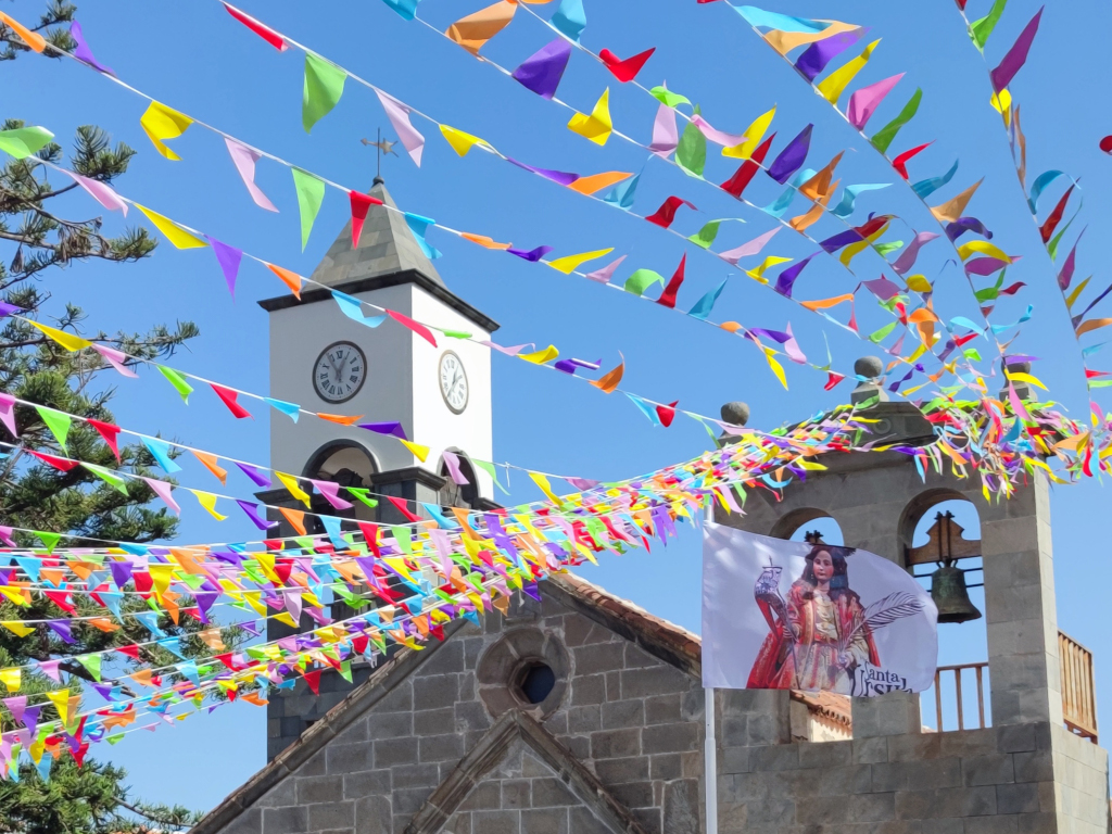 Torre de iglesia en Tenerife con banderines coloridos y bandera de Santa Úrsula.