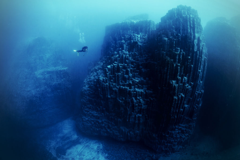 Buzo nadando cerca de columnas basálticas submarinas en Tenerife.