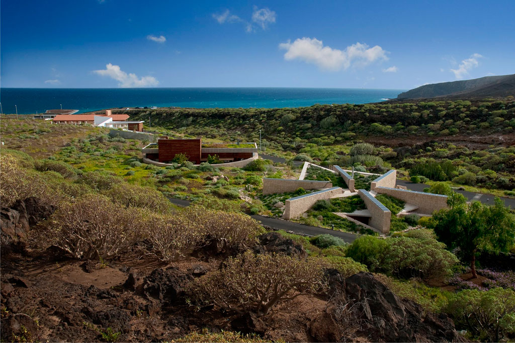 Centro de visitantes en Punta de Teno, Tenerife, rodeado de vegetación y mar al fondo.