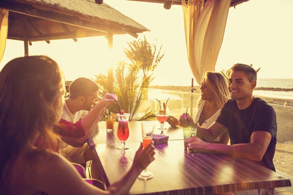 Personas disfrutando cócteles al atardecer en una terraza en Tenerife.