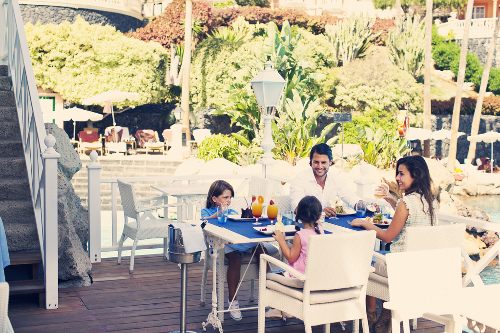 Familia disfrutando almuerzo al aire libre en un restaurante en Tenerife.