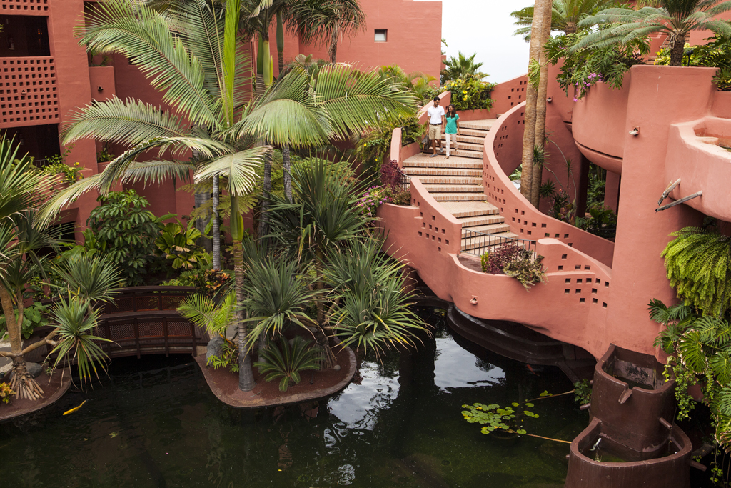Personas suben escaleras en entorno tropical de hotel en Tenerife.