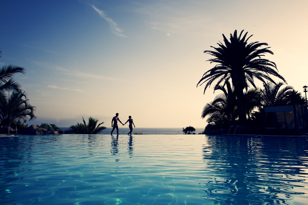 Pareja caminando junto a una piscina al atardecer en Tenerife.