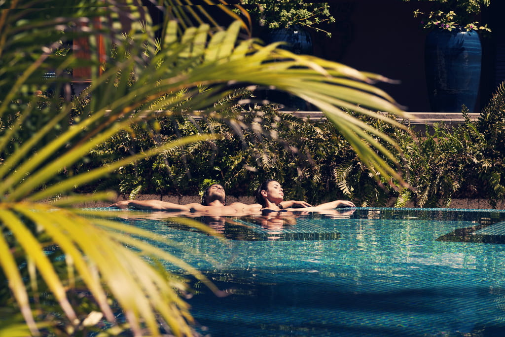 Personas relajándose en la piscina rodeada de vegetación en Tenerife.