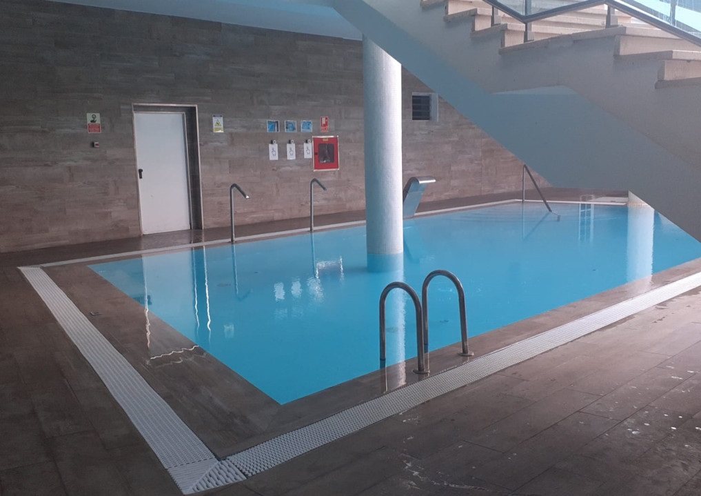 Piscina interior con escaleras y letreros en la pared en Tenerife.