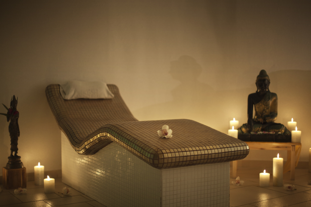 Camilla de masaje con velas y estatua en spa de Tenerife.