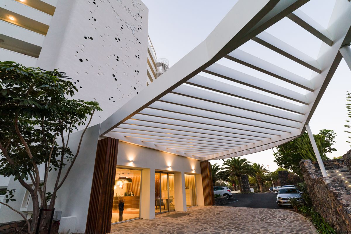 Entrada moderna de un hotel en Tenerife con estructura de techo blanca.