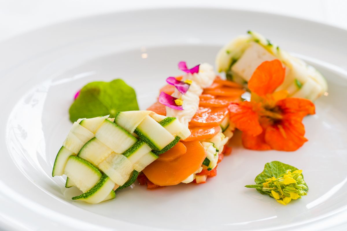 Plato gourmet con verduras adornadas con flores coloridas, Tenerife.