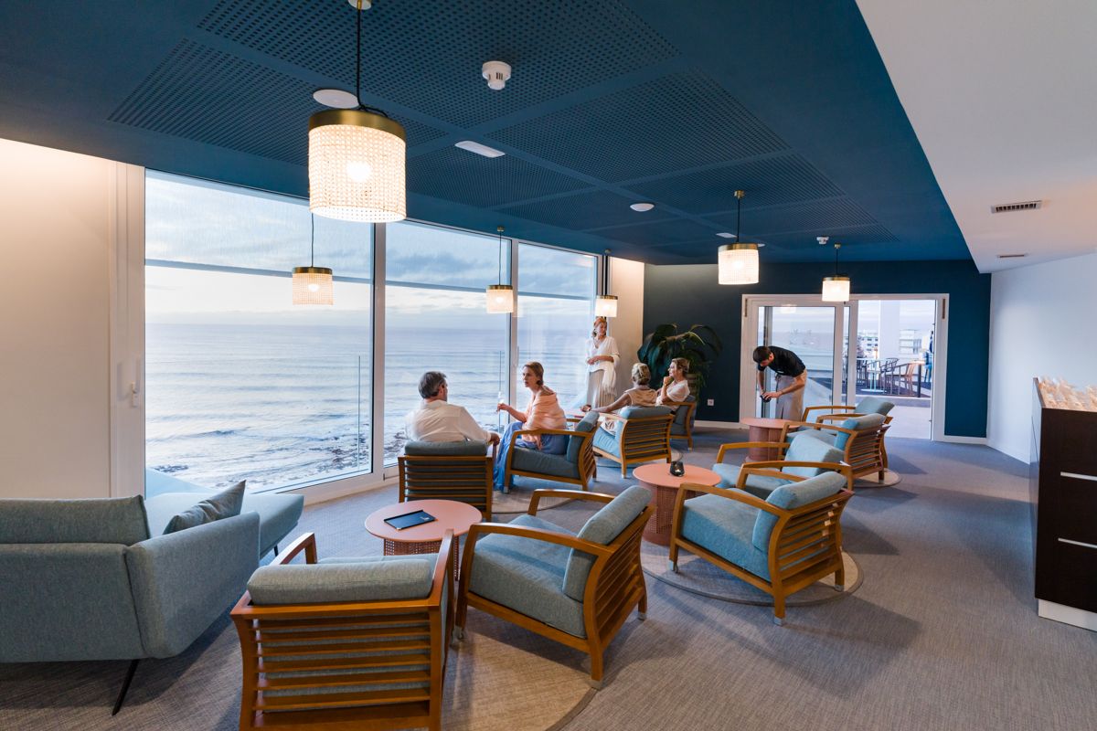 Personas conversan en un salón con vista al mar en Tenerife.