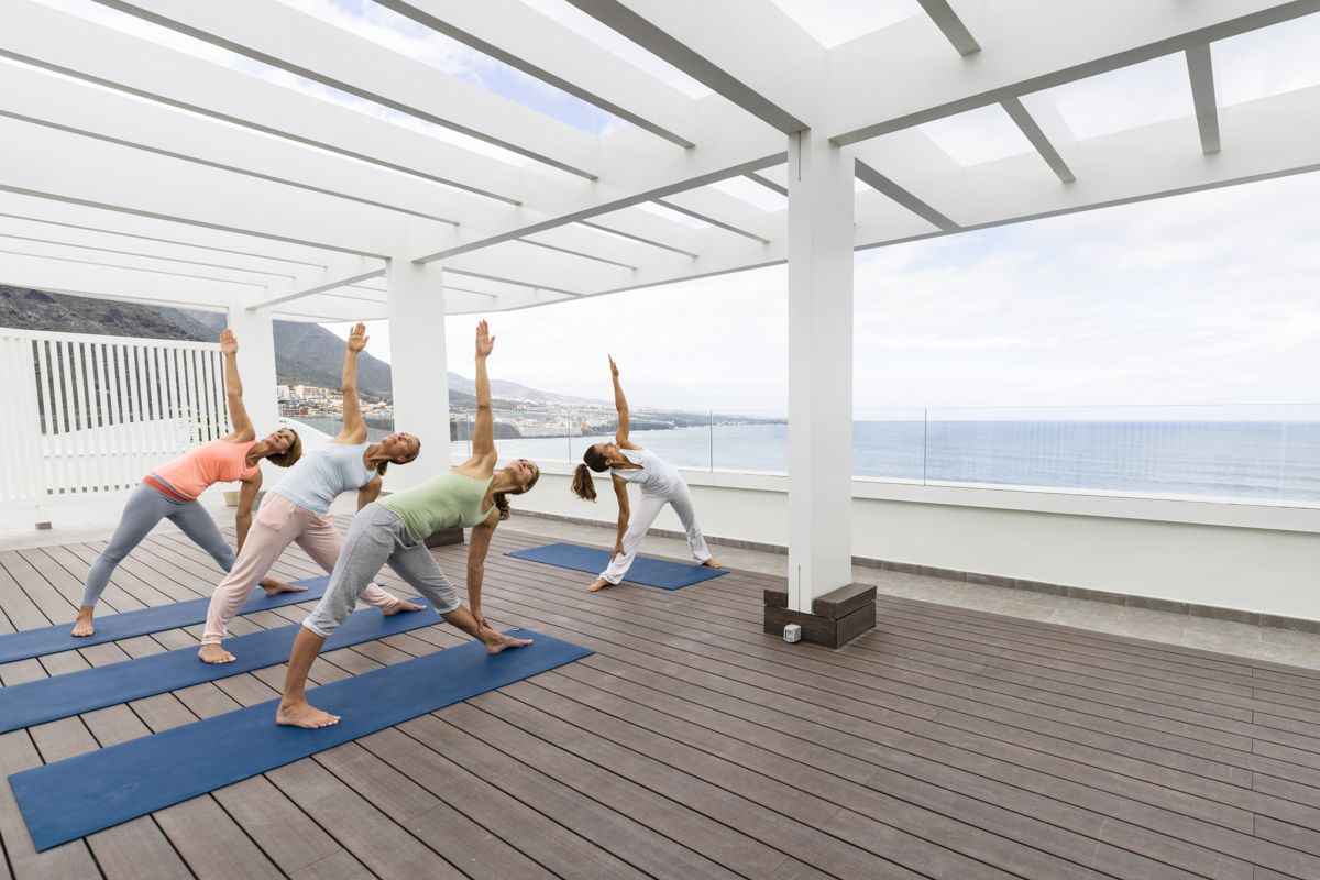 Grupo practicando yoga al aire libre con vistas al mar en Tenerife.