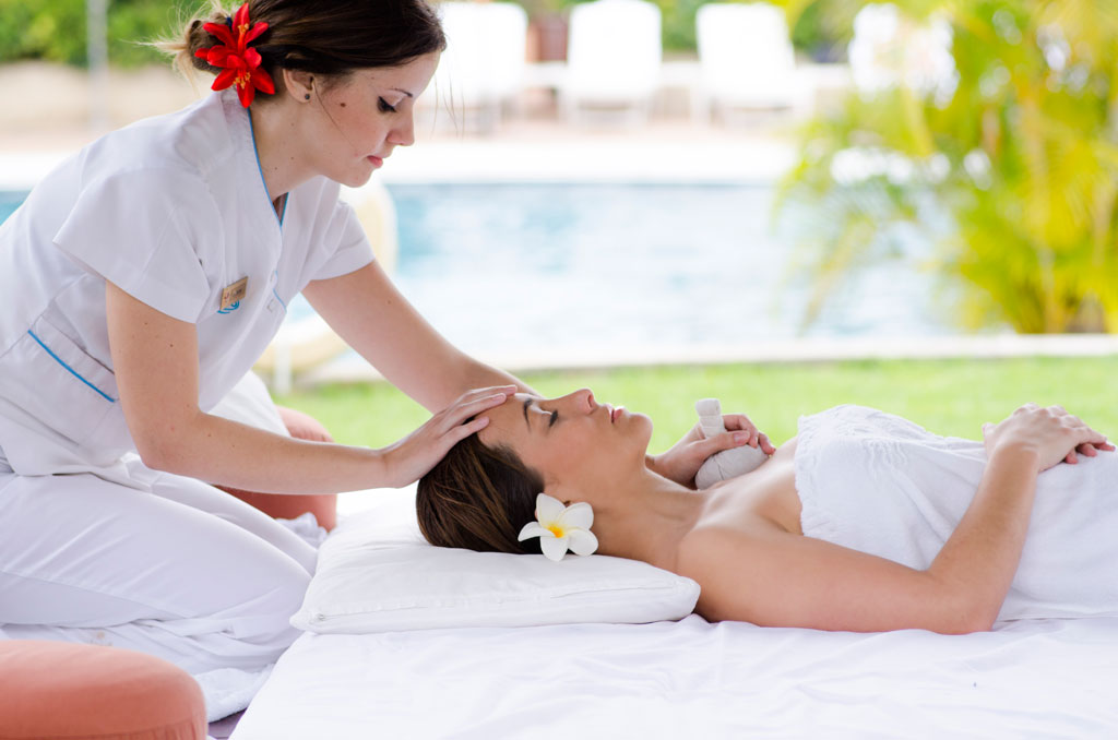 Terapeuta da un masaje a mujer recostada junto a piscina en Tenerife.